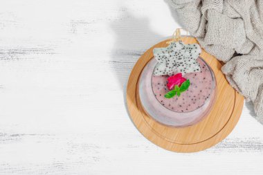 Pitaya smoothie, sağlıklı detoks içeceği. Moda içecek, yararlı kahvaltı fikri. Sert ışık, karanlık gölge, beyaz ahşap zemin, üst manzara