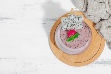 Pitaya smoothie, sağlıklı detoks içeceği. Moda içecek, yararlı kahvaltı fikri. Sert ışık, karanlık gölge, beyaz ahşap zemin, üst manzara