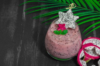 Pitaya smoothie, sağlıklı detoks içeceği. Moda içecek, yararlı kahvaltı fikri. Sert ışık, karanlık gölge, siyah ahşap zemin, kopyalama alanı