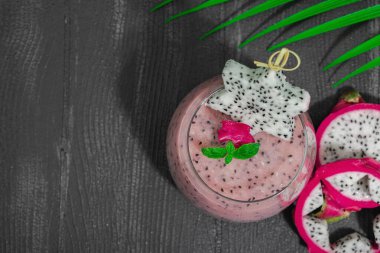 Pitaya smoothie, sağlıklı detoks içeceği. Moda içecek, yararlı kahvaltı fikri. Sert ışık, karanlık gölge, siyah ahşap arka plan, üst manzara