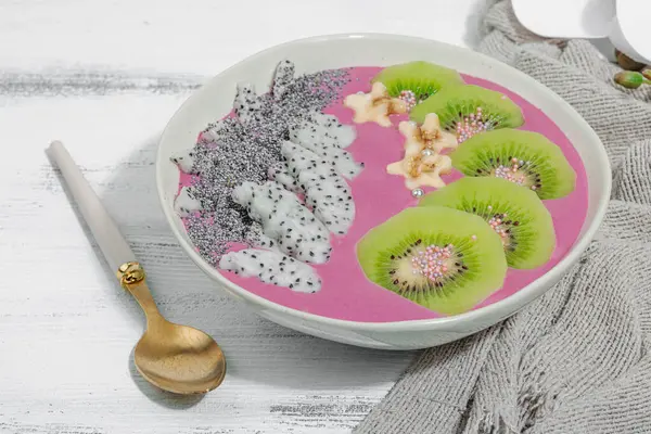 Meyve, kivi, muz ve haşhaş tohumlu Pitaya smoothie kasesi. Moda yemek, sağlıklı kahvaltı fikri. Sert ışık, karanlık gölge, beyaz ahşap zemin, kopyalama alanı