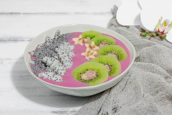 Meyve, kivi, muz ve haşhaş tohumlu Pitaya smoothie kasesi. Moda yemek, sağlıklı kahvaltı fikri. Sert ışık, karanlık gölge, beyaz ahşap zemin, kopyalama alanı