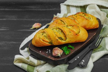 Taze sarımsaklı ekmek, glütensiz çörek. Lezzetli yemekler, taze maydanoz, mis kokulu baharatlar. Ev yapımı fırın, hazırlık tostları için malzeme. Siyah tahta tahtalar, boşluğu kopyala