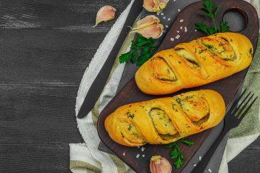 Taze sarımsaklı ekmek, glütensiz çörek. Lezzetli yemekler, taze maydanoz, mis kokulu baharatlar. Ev yapımı fırın, hazırlık tostları için malzeme. Siyah ahşap tahtalar, üst manzara.