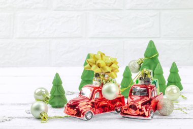 Yaratıcı Noel kompozisyonu. Geleneksel Yeni Yıl dekorasyonu, bayram sembolleri. Retro kırmızı arabalar, el yapımı köknar ağaçları, beyaz arka plan, bayram tebrik kartı, kopyalama alanı.