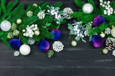 Yeni yılın kutlu olsun. Şenlikli Noel mücevherleri, her zaman yeşil dallar, kozalaklar, karlı meyveler. Siyah ahşap arkaplan, tebrik kartı, düz yatak, üst manzara