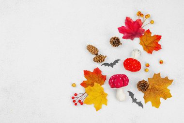 Cadılar Bayramı zanaatı. Yumuşak dikişli mantarlar, akçaağaç yaprakları, dekoratif böğürtlen ve yarasalar. Işık arkaplan, üst görünüm