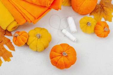 Cadılar Bayramı zanaatı. Yumuşak dikiş balkabakları, yaratıcı süreç, profesyonel aletler ve malzemeler. Işık arkaplan, üst görünüm