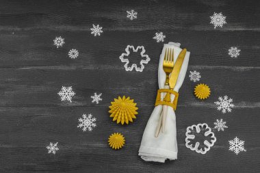 Yeni yıl sofrası. Noel çatal bıçak takımı, altın kış dekorasyonu, düz yatak. Neşeli bir ortam, siyah taş beton arka plan, üst manzara.