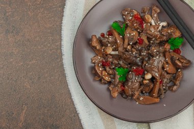 Delicious Shimeji and Oyster mushrooms with chili pepper, sesame seeds and greens. Served portion, healthy Umami vegan food, East Asia style. Brown stone concrete background, top view clipart