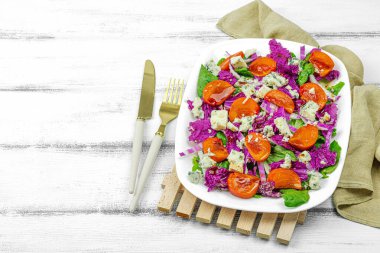 Mor Napa lahanasından sağlıklı salata, hurma, marul, rokfor peyniri ve sos. Taze sebzeler, lezzetli yemekler. Beyaz ahşap zemin, düz yatış, kopyalama alanı