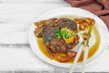 Ossobuco beef meat with spices and fresh herbs. Veal shank steak, traditional Italian ingredient for cooking healthy food. White wooden background, copy space clipart