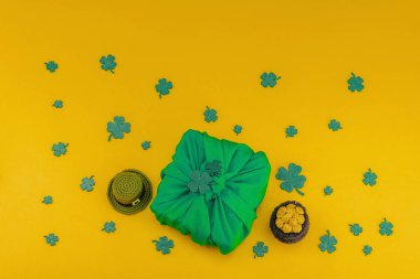 El yapımı Aziz Patrick Günü hediyesi konsepti. Furoshiki, geleneksel dekoratif semboller, tığ işi leprikon şapka, altın sikkeli tencere, düz yatak, üst manzara.