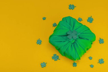 El yapımı Aziz Patrick Günü hediyesi konsepti. Furoshiki, geleneksel dekoratif semboller, tığ işi leprikon şapka, altın sikkeli tencere, düz yatak, üst manzara.