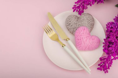 El yapımı kalpleri ve leylak çiçekleri olan yumuşak bahar sofrası. Sevgililer Günü ya da anneler günü, geleneksel bayram sembolü, tebrik kartı. Pastel pembe arkaplan, düz yatış, üst görünüm
