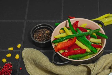 Canlı donmuş sebze karışımı, sarı ve yeşil fasulye, kırmızı dolmalık biber, mısır. Soğuk dokular, çeşitli baharatlar, vejetaryen yaşam tarzı. Siyah karo arkaplan, düz yatış, kopyalama alanı