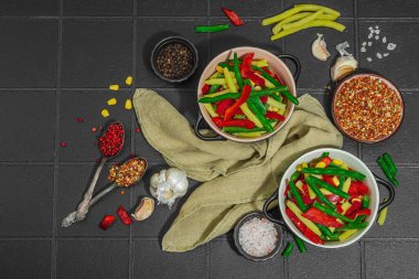 Canlı donmuş sebze karışımı, sarı ve yeşil fasulye, kırmızı dolmalık biber, mısır. Soğuk dokular, çeşitli baharatlar, vejetaryen yaşam tarzı. Siyah karo arkaplan, düz yatay, üst görünüm