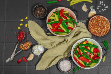 Canlı donmuş sebze karışımı, sarı ve yeşil fasulye, kırmızı dolmalık biber, mısır. Soğuk dokular, çeşitli baharatlar, vejetaryen yaşam tarzı. Siyah karo arkaplan, düz yatay, üst görünüm