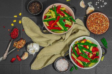 Canlı donmuş sebze karışımı, sarı ve yeşil fasulye, kırmızı dolmalık biber, mısır. Soğuk dokular, çeşitli baharatlar, vejetaryen yaşam tarzı. Siyah karo arkaplan, düz yatay, üst görünüm