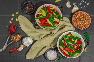 Canlı donmuş sebze karışımı, sarı ve yeşil fasulye, kırmızı dolmalık biber, mısır. Soğuk dokular, çeşitli baharatlar, vejetaryen yaşam tarzı. Siyah karo arkaplan, düz yatay, üst görünüm