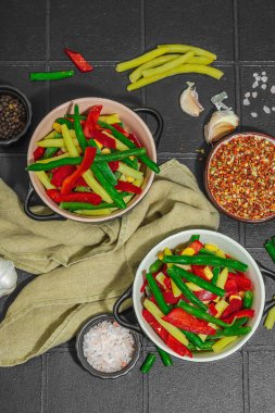 Canlı donmuş sebze karışımı, sarı ve yeşil fasulye, kırmızı dolmalık biber, mısır. Soğuk dokular, çeşitli baharatlar, vejetaryen yaşam tarzı. Siyah karo arkaplan, düz yatay, üst görünüm