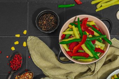 Canlı donmuş sebze karışımı, sarı ve yeşil fasulye, kırmızı dolmalık biber, mısır. Soğuk dokular, çeşitli baharatlar, vejetaryen yaşam tarzı. Siyah karo arkaplan, düz yatay, üst görünüm