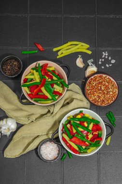 Canlı donmuş sebze karışımı, sarı ve yeşil fasulye, kırmızı dolmalık biber, mısır. Soğuk dokular, çeşitli baharatlar, vejetaryen yaşam tarzı. Siyah karo arkaplan, düz yatay, üst görünüm