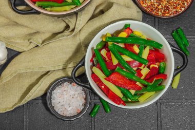 Canlı donmuş sebze karışımı, sarı ve yeşil fasulye, kırmızı dolmalık biber, mısır. Soğuk dokular, çeşitli baharatlar, vejetaryen yaşam tarzı. Siyah karo arkaplan, düz yatay, üst görünüm