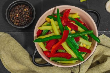 Canlı donmuş sebze karışımı, sarı ve yeşil fasulye, kırmızı dolmalık biber, mısır. Soğuk dokular, çeşitli baharatlar, vejetaryen yaşam tarzı. Siyah karo arkaplan, düz yatay, üst görünüm