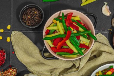 Canlı donmuş sebze karışımı, sarı ve yeşil fasulye, kırmızı dolmalık biber, mısır. Soğuk dokular, çeşitli baharatlar, vejetaryen yaşam tarzı. Siyah karo arkaplan, düz yatay, üst görünüm