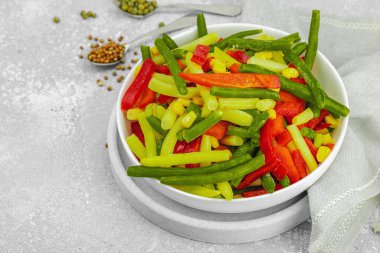 Canlı donmuş sebze karışımı, sarı ve yeşil fasulye, kırmızı dolmalık biber, mısır. Soğuk dokular, çeşitli baharatlar, vejetaryen yaşam tarzı. Hafif taş arkaplan, düz yatış, kopyalama alanı