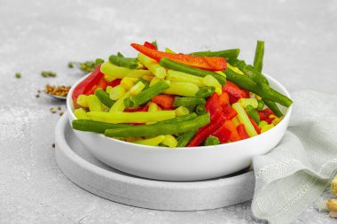 Canlı donmuş sebze karışımı, sarı ve yeşil fasulye, kırmızı dolmalık biber, mısır. Soğuk dokular, çeşitli baharatlar, vejetaryen yaşam tarzı. Hafif taş zemin, düz zemin, yakın plan.