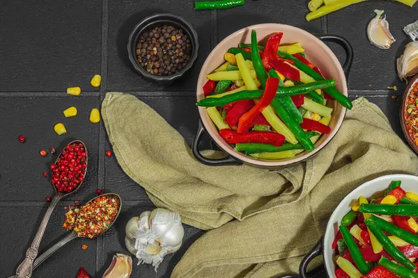 Canlı donmuş sebze karışımı, sarı ve yeşil fasulye, kırmızı dolmalık biber, mısır. Soğuk dokular, çeşitli baharatlar, vejetaryen yaşam tarzı. Siyah karo arkaplan, düz yatay, üst görünüm