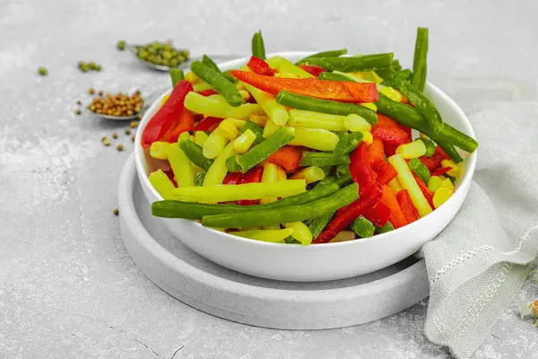 Canlı donmuş sebze karışımı, sarı ve yeşil fasulye, kırmızı dolmalık biber, mısır. Soğuk dokular, çeşitli baharatlar, vejetaryen yaşam tarzı. Hafif taş arkaplan, düz yatış, kopyalama alanı