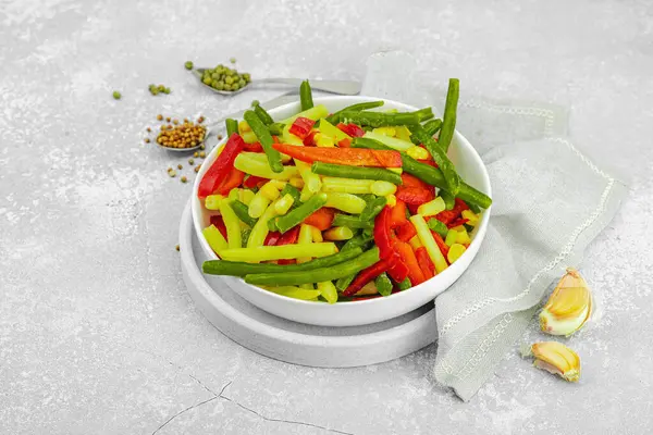 Canlı donmuş sebze karışımı, sarı ve yeşil fasulye, kırmızı dolmalık biber, mısır. Soğuk dokular, çeşitli baharatlar, vejetaryen yaşam tarzı. Hafif taş arkaplan, düz yatış, kopyalama alanı