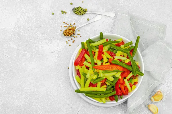 Canlı donmuş sebze karışımı, sarı ve yeşil fasulye, kırmızı dolmalık biber, mısır. Soğuk dokular, çeşitli baharatlar, vejetaryen yaşam tarzı. Hafif taş zemin, düz zemin, üst manzara