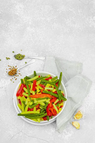 Canlı donmuş sebze karışımı, sarı ve yeşil fasulye, kırmızı dolmalık biber, mısır. Soğuk dokular, çeşitli baharatlar, vejetaryen yaşam tarzı. Hafif taş zemin, düz zemin, üst manzara