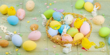 Canlı Paskalya konsepti. Geleneksel bayram sembolleri. Yumurtalar, tavşanlar ve kuşlar. Yaratıcı düz döşeme, yeşil fayans arkaplan, pankart biçimi