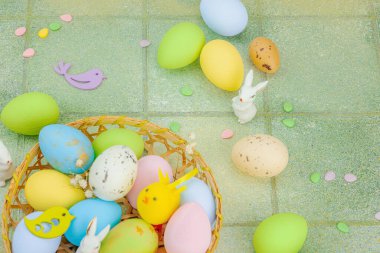 Canlı Paskalya konsepti. Geleneksel bayram sembolleri. Yumurtalar, tavşanlar ve kuşlar. Yaratıcı düz döşeme, yeşil fayans arkaplan, üst görünüm