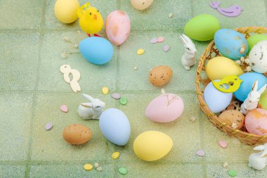 Canlı Paskalya konsepti. Geleneksel bayram sembolleri. Yumurtalar, tavşanlar ve kuşlar. Yaratıcı düz döşeme, yeşil fayans arkaplan, kopyalama alanı