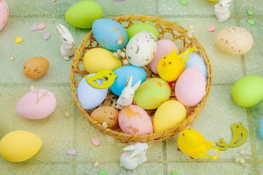 Canlı Paskalya konsepti. Geleneksel bayram sembolleri. Yumurtalar, tavşanlar ve kuşlar. Yaratıcı düz döşeme, yeşil fayans arkaplan, üst görünüm