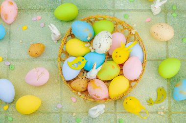 Canlı Paskalya konsepti. Geleneksel bayram sembolleri. Yumurtalar, tavşanlar ve kuşlar. Yaratıcı düz döşeme, yeşil fayans arkaplan, üst görünüm