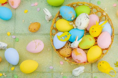 Canlı Paskalya konsepti. Geleneksel bayram sembolleri. Yumurtalar, tavşanlar ve kuşlar. Yaratıcı düz döşeme, yeşil fayans arkaplan, üst görünüm
