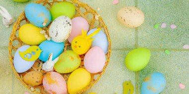 Canlı Paskalya konsepti. Geleneksel bayram sembolleri. Yumurtalar, tavşanlar ve kuşlar. Yaratıcı düz döşeme, yeşil fayans arkaplan, pankart biçimi