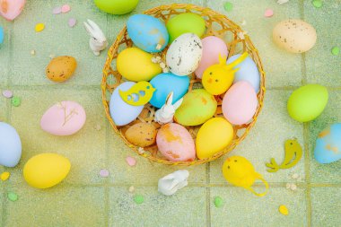 Canlı Paskalya konsepti. Geleneksel bayram sembolleri. Yumurtalar, tavşanlar ve kuşlar. Yaratıcı düz döşeme, yeşil fayans arkaplan, üst görünüm