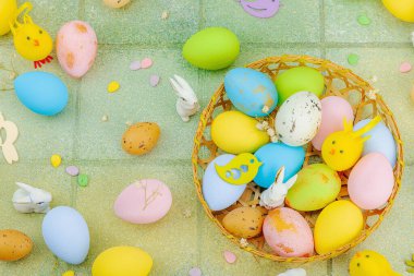 Canlı Paskalya konsepti. Geleneksel bayram sembolleri. Yumurtalar, tavşanlar ve kuşlar. Yaratıcı düz döşeme, yeşil fayans arkaplan, üst görünüm