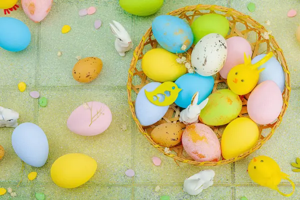 Canlı Paskalya konsepti. Geleneksel bayram sembolleri. Yumurtalar, tavşanlar ve kuşlar. Yaratıcı düz döşeme, yeşil fayans arkaplan, üst görünüm