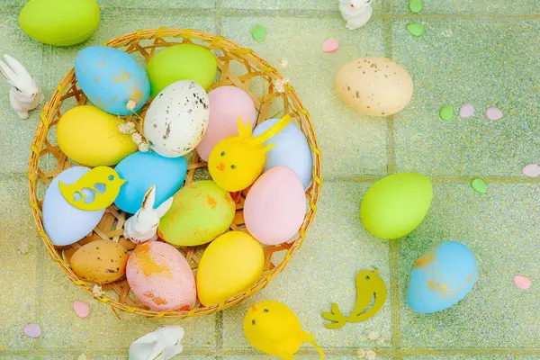 Canlı Paskalya konsepti. Geleneksel bayram sembolleri. Yumurtalar, tavşanlar ve kuşlar. Yaratıcı düz döşeme, yeşil fayans arkaplan, üst görünüm