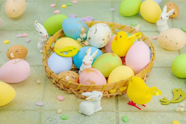 Canlı Paskalya konsepti. Geleneksel bayram sembolleri. Yumurtalar, tavşanlar ve kuşlar. Yaratıcı düz döşeme, yeşil fayans arkaplan, kapat