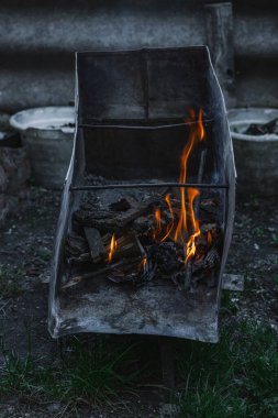Kötü yaşam koşullarında ısıtmak ya da pişirmek için kullanılan metal bir kapta ateş açın. Kentsel yoksulluğu, yer değiştirmeyi ve kriz ortamlarında hayatta kalmayı yansıtıyor